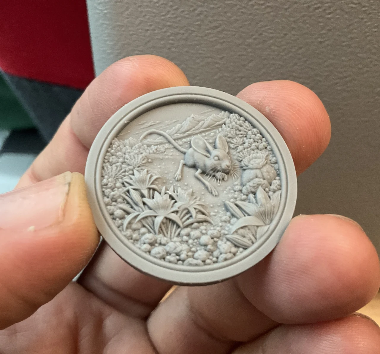 A hand holding the creator’s finished circular mouse relief